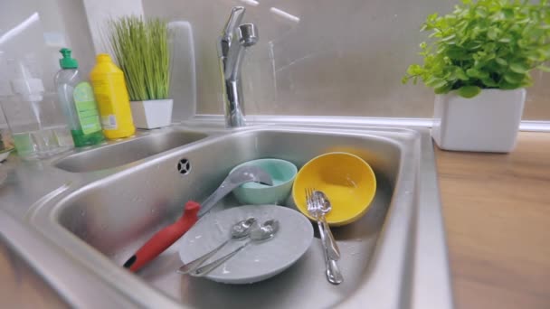 Rutin eljárás a konyhában. Mocskos edények a mosogatóban. A csapvíz piszkos edényekre ömlik. Mosogatási folyamat. Házi feladat — Stock videók