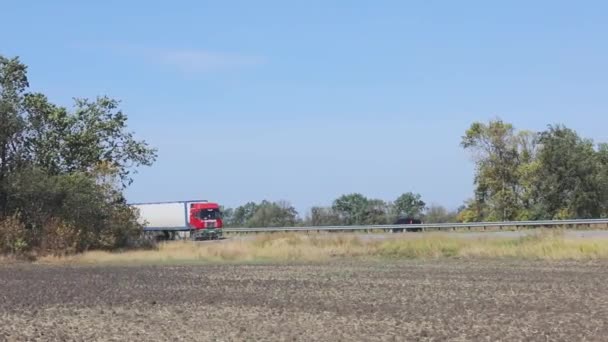 El camión conduce por la carretera alrededor de los campos y árboles. El camión está conduciendo por la carretera. — Vídeo de stock