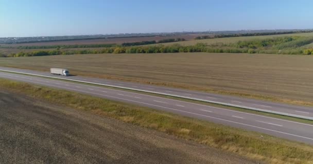 De truck rijdt op de weg, velden op de achtergrond. De truck rijdt langs de weg in het midden van landbouwvelden bovenaanzicht. — Stockvideo