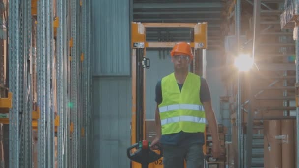 Modern special equipment in stock. A worker transports a load on an electric hydraulic forklift. Large modern warehouse. — Stock Video