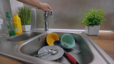 Bulaşık yıkama işlemi. Ev ödevi. Kirli bulaşıklar lavaboda. Mutfakta rutin işler. Çeşme suyu kirli tabaklara dökülür..