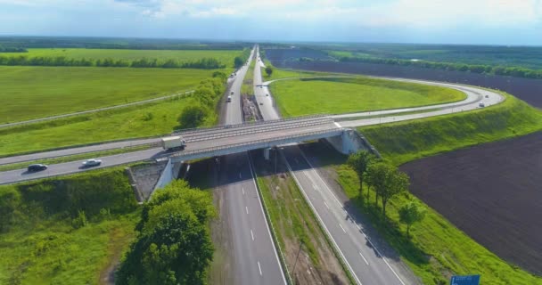 Stor väg med bilar ovanifrån i bra väder. Bilar kör längs motorvägen utanför staden. Transportutbyte på motorvägen. — Stockvideo