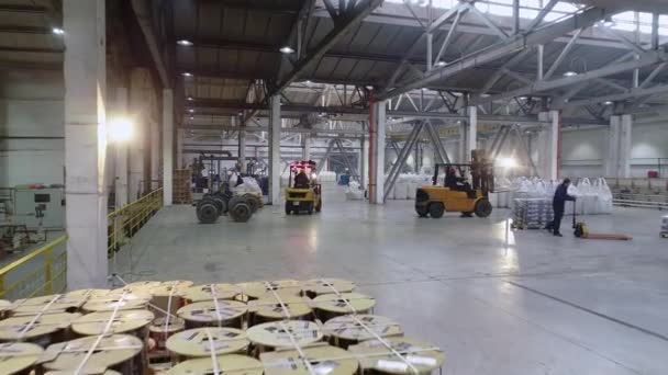 Montacargas en un gran almacén, flujo de trabajo activo en el almacén. Las carretillas elevadoras se mueven en un gran almacén luminoso — Vídeos de Stock