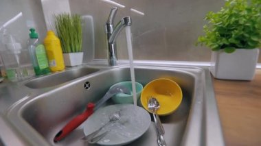 Mutfakta rutin işler. Kirli bulaşıklar lavaboda. Musluk suyu kirli tabaklara dökülür. Bulaşık yıkama işlemi. Ev ödevi