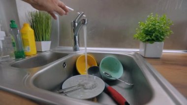 Kirli bulaşıklar lavaboda. Mutfakta rutin işler. Musluk suyu kirli tabaklara dökülür. Bulaşık yıkama işlemi. Ev ödevi