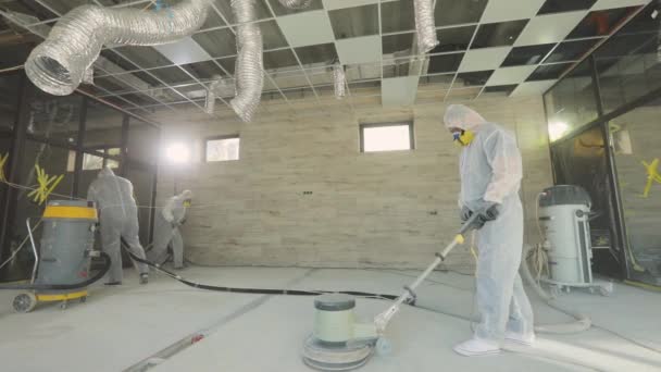 Os construtores estão a polir o chão com equipamento especial. Moagem de superfície de concreto. Construtores em um canteiro de obras — Vídeo de Stock