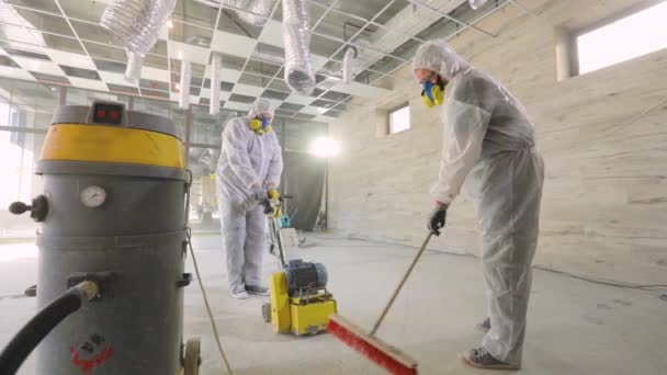 Bauarbeiter polieren den Boden mit Spezialgeräten. Betonoberflächenschleifen. Bauarbeiter auf einer Baustelle — Stockvideo
