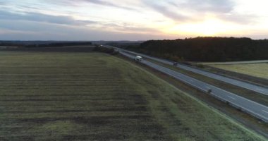 Kamyon alacakaranlıkta tarlaların arasında yol boyunca gider. Kamyon gün batımında yol boyunca sürüyor. Akşam yolu.
