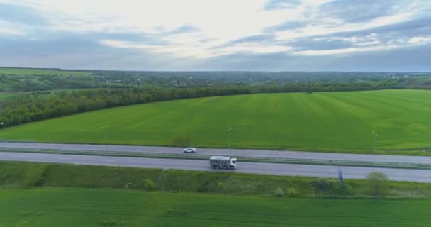 Náklaďák jede po moderní dálnici kolem zeleného travnatého výhledu. Náklaďák na dálnici pohled z dronu. — Stock video