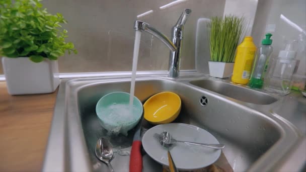 Routine in the kitchen. Dirty dishes in the sink. Tap water pours onto dirty dishes. Dishwashing process. Homework — Stock Video