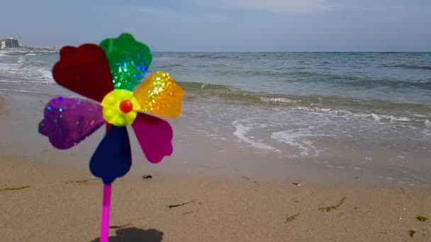 Moinho de vento infantil no mar. Moinho de vento infantil. Um moinho de vento colorido das crianças está girando na costa. — Vídeo de Stock