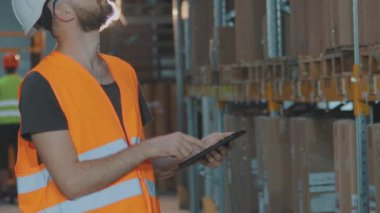 Depoda tabletli bir yönetici malları kontrol ediyor. Büyük bir fabrikanın depo müdürü..