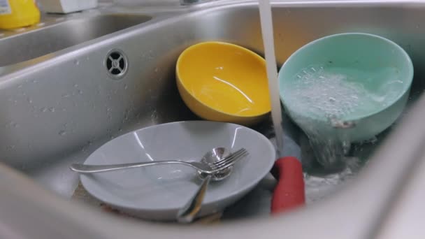 Tap water pours onto dirty dishes. Dishwashing process. Dirty dishes in the sink. Routine in the kitchen. Homework — Stock Video