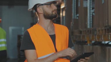 Bir adam ağır çekimde depodan geçiyor. Bir işçi ağır çekimde modern bir depoda yürüyor.