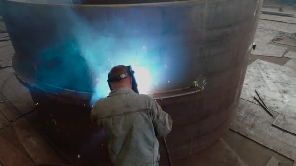 A welder welds a metal part, top view. Welder in the workshop of the plant. Working process at a metalworking factory. — Stock Video