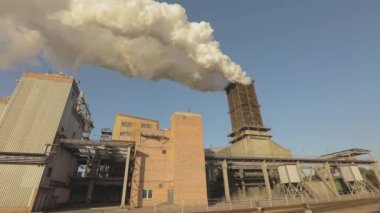Bitkinin bacasından çıkan kalın beyaz duman. Çevreye zarar vermek. Büyük bir metalürjik bitkinin dışı. Bitkinin bacasından beyaz duman emisyonu.