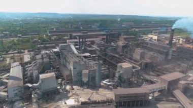 Dumanı tüten bacası olan büyük bir metal bitkinin üzerinden uçmak. Fabrikanın bacasından duman salınımı. Fabrika insansız hava aracı görüntüsünün bacasından yoğun duman çıkıyor.
