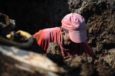 Bükreş, Romanya - 21 Nisan 2010: Bükreş 'te asfaltsız bir yol üzerinde kanalizasyon ve su boru hattı üzerinde çalışan adam.