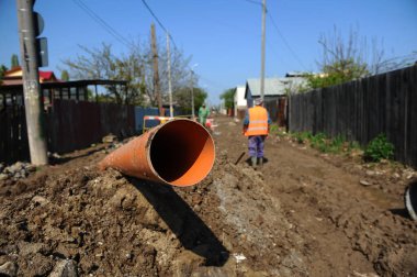 Bükreş, Romanya - 21 Nisan 2010: Bükreş 'te asfaltsız bir yol üzerinde kanalizasyon ve su boru hattı üzerinde çalışan adam.