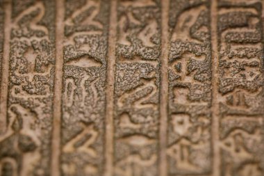 Shallow depth of field (selective focus) and close up image with Egyptian hieroglyphs on a historic replica. clipart