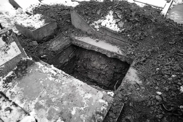 Empty grave in a cemetery during a cold and snowy winter day.