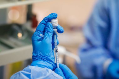 Bükreş, Romanya - 15 Ocak 2021: Bir doz Pfizer BioNTech anti-Covid 19 aşısı hazırlayan bir sağlık çalışanının elleriyle ayrıntılar.