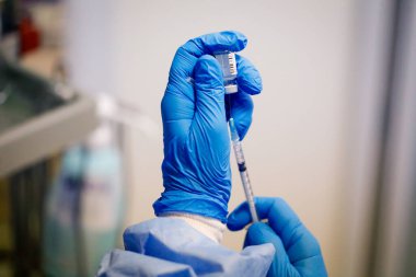 Bükreş, Romanya - 15 Ocak 2021: Bir doz Pfizer BioNTech anti-Covid 19 aşısı hazırlayan bir sağlık çalışanının elleriyle ayrıntılar.