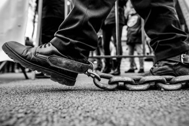 Bükreş 'te düzenlenen bir protesto sırasında paslı metal bir zinciri ayaklarına bağlayan polisin sığ alan derinliği (seçici odak) ayrıntıları.
