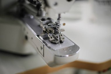 Bir tekstil fabrikasında elektrikli dikiş makinesiyle sığ alan derinliği (seçici odak) resmi.