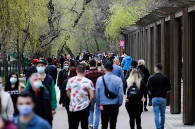 Bükreş, Romanya - 28 Mart 2021: Covid-19 salgın kısıtlamaları sırasında IOR parkında yürüyüş yapan insanların sığ alan derinliği (seçici odak) resmi.