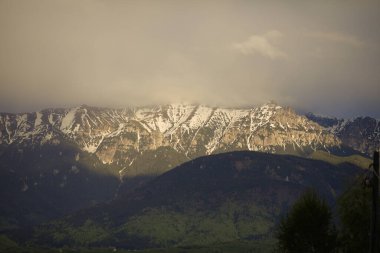 Romanya 'daki Bucegi dağları üzerinde bir bahar günü Pestera köyünün tepelerinden görülen ağır bulutlar görülüyor.
