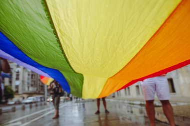 İnsanlar bir LGBTQ gay gururu protestosu sırasında gökkuşağı pankartı taşıyor.