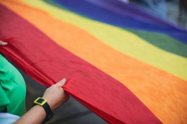 İnsanlar bir LGBTQ gay gururu protestosu sırasında gökkuşağı pankartı taşıyor.