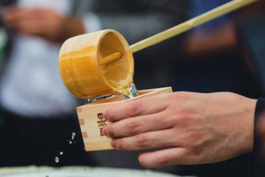 Braila, Romanya - 26 Ağustos 2021: Geleneksel Japon sake 'sini ahşap bir fincana döken bir adamın elleriyle ayrıntılar.