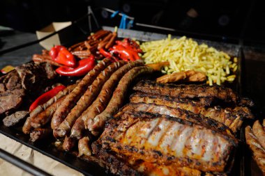 Kömür metal ızgarasında et ürünleri (mici, domuz pirzolası, sosis, patates kızartması).