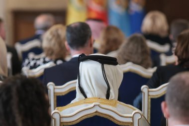 Seyirciler arasında Müslüman Ghutra, Shemagh, Keffiyeh giyen Agal adında siyah bir kordonla tutulan kare bir pamuk atkı giyen bir adamla derin alan detayları..