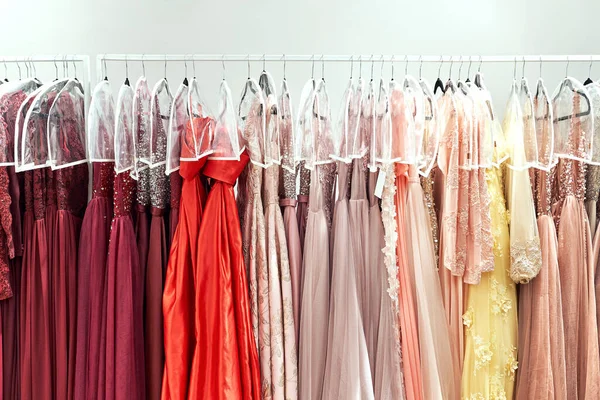 Varios vestidos en diferentes colores en perchas en un servicio de alquiler —  Fotos de Stock