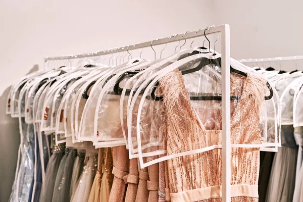 Various dresses in different colors on hangers in a rental service — Stock Photo, Image