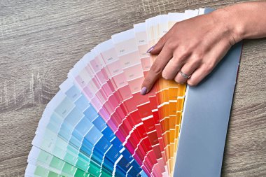 Renk tonunu seçmek için renk çarkı. Renkleri seçmek için paletle çalışan kadın iç mimar elleri. Yaratıcı süreç konsepti. Renklerle eşleşen seçenekler karşılaştırılıyor.