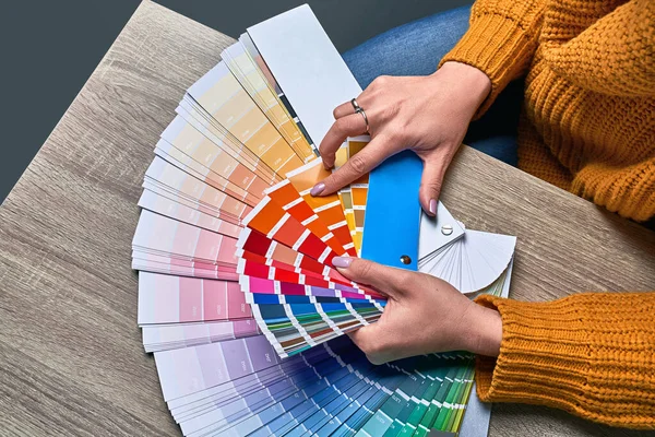 페인트 톤을 선택하기 위한 컬러 휠. 색을 선택하기 위해 팔레트를 사용하는 여성 인테리어 디자이너의 손. 창조적 인 과정의 개념. 일치하는 색상과 선택 사항을 비교. — 스톡 사진