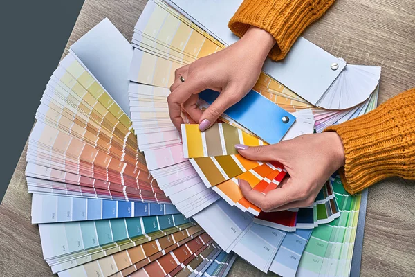 Color wheel for choosing paint tone. Hands of female interior designer working with palette for choosing colors. Creative process concept. Comparing options with matching hues. — Stock Photo, Image