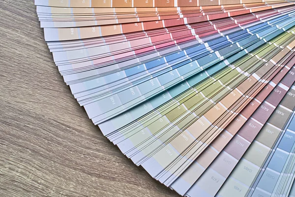 Color wheel palette for choosing paint tone. Various colors on wooden table background with copy space. Interior designer tool.
