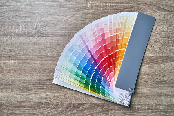 Color wheel palette for choosing paint tone. Various colors on wooden table background with copy space. Interior designer tool.