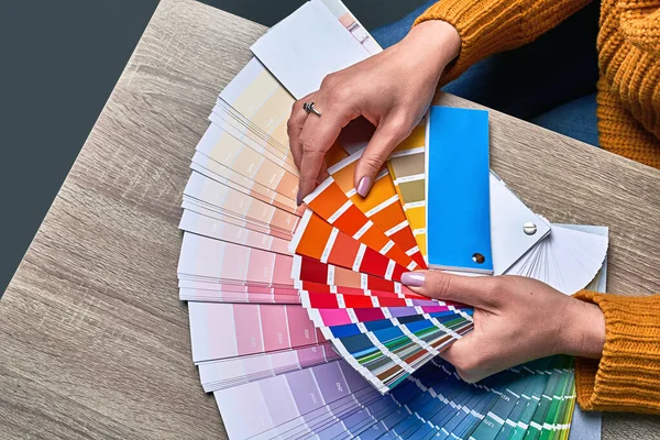 Color wheel for choosing paint tone. Hands of female interior designer working with palette for choosing colors. Creative process concept. Comparing options with matching hues. — Stock Photo, Image