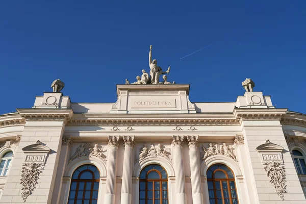 Facciata superiore dell'edificio principale dell'Università di Tecnologia di Varsavia su sfondo cielo blu con aereo volante. Varsavia, Polonia. — Foto Stock