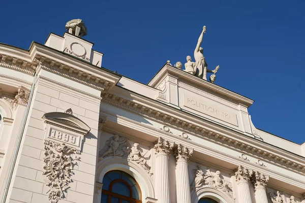 Facciata superiore dell'edificio principale dell'Università di Tecnologia di Varsavia su sfondo cielo blu con aereo volante. Varsavia, Polonia. — Foto Stock