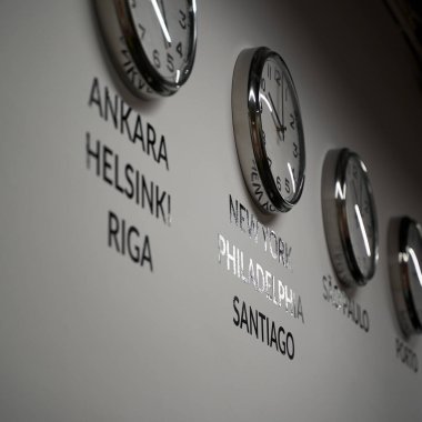 İş dünyasının beyaz duvarında dünyanın farklı şehirlerinin zamanlarını gösteren birçok duvar saati var.