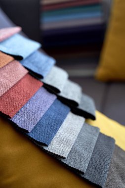 Kanepenin üzerinde renkli kumaş örnekleri var.