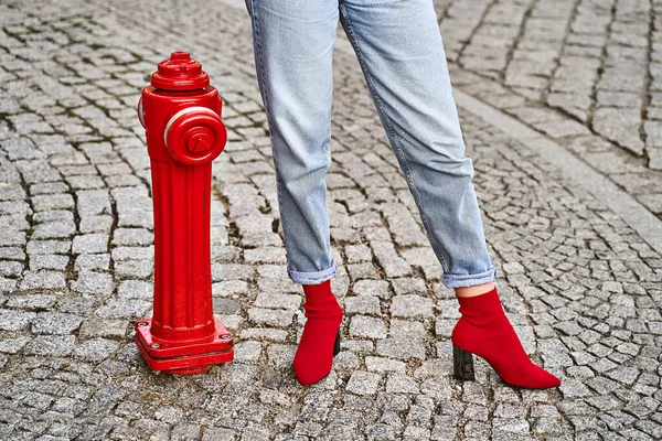 Pernas de mulher em vermelho tecido de malha calcanhar calcanhar sapatos meia e calças jeans jeans azul perto de rua vermelha fogo hidrante — Fotografia de Stock