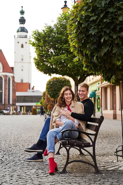 Hermosa pareja joven abrazándose en un banco en una ciudad europea. Cita romántica y concepto de amor. — Foto de Stock